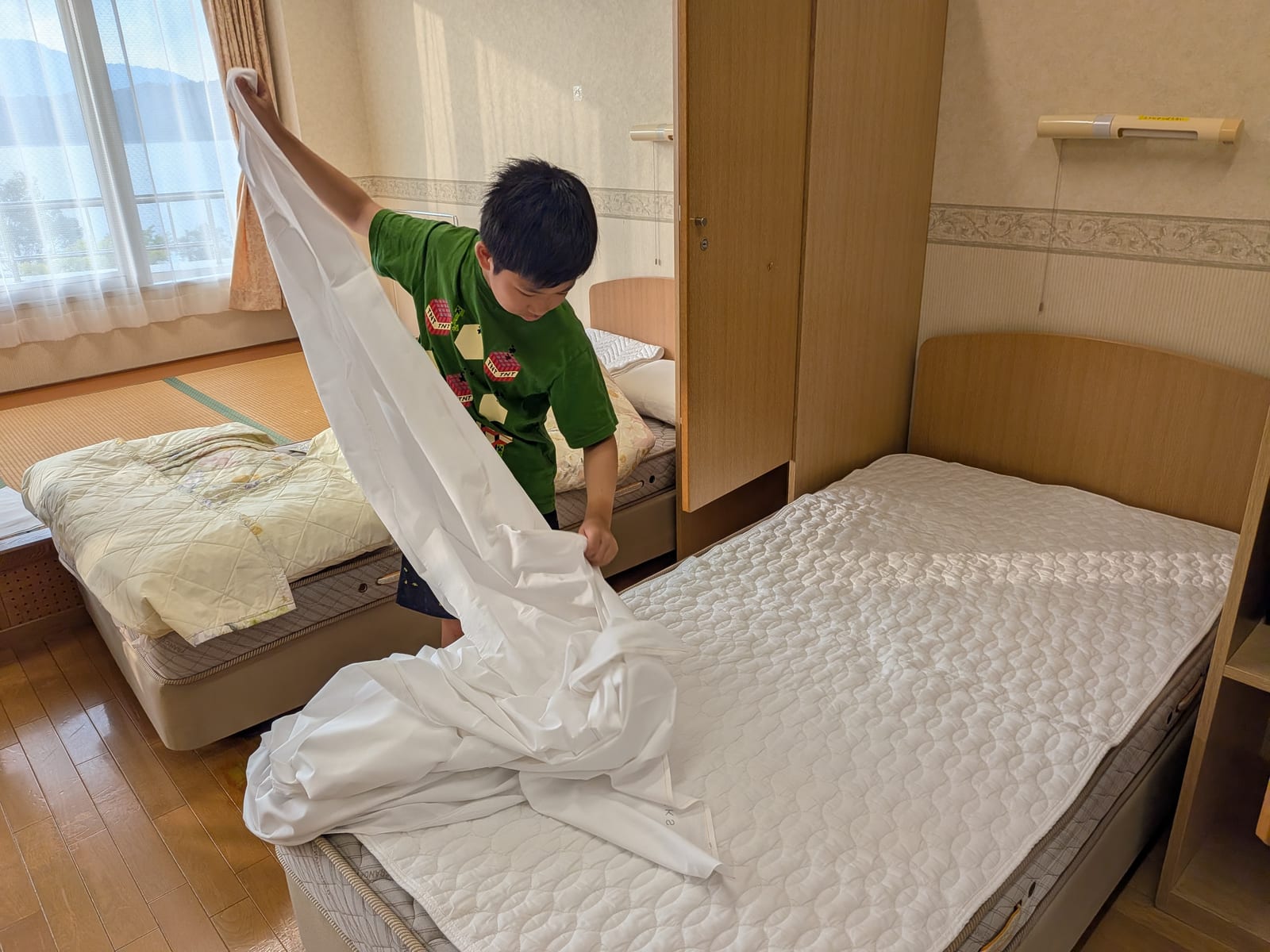 シーツを広げてベッドメイキング